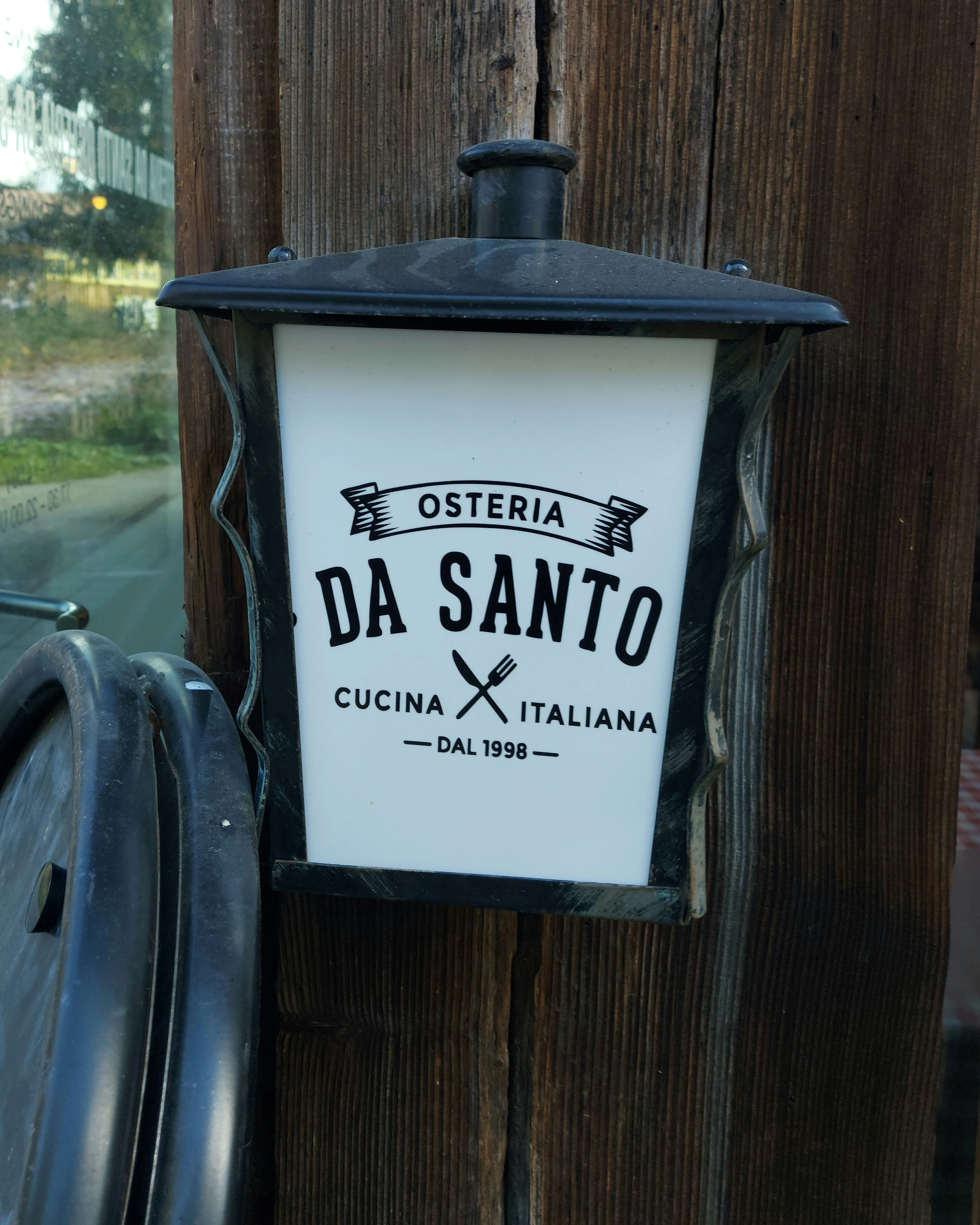 Beschilderung und Logo der Osteria da Santo am Holzgebäude