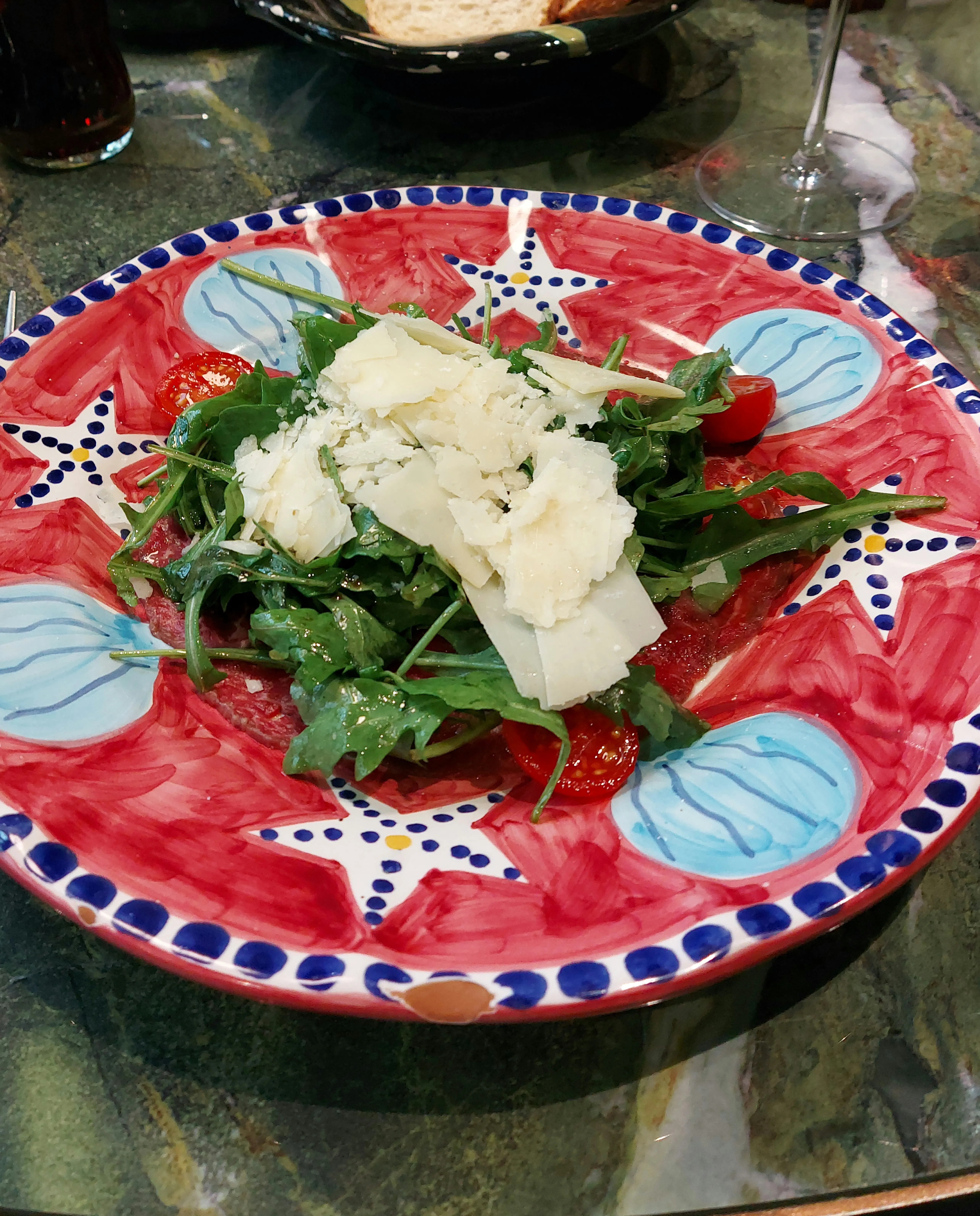 Carpaccio with rocket, grana, and dressing at Galleria Luce Bern – served on a white plate