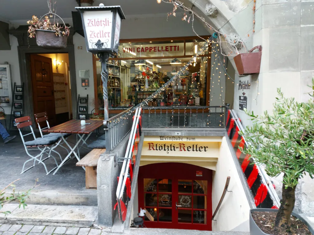 Small terrace under the Bernese arcades next to the open cellar door and the traditional lantern of Klötzlikeller