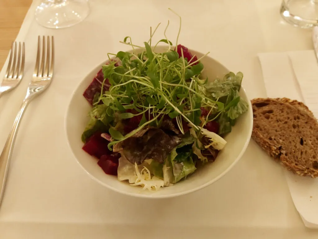 A small green leaf salad garnished with fresh cress in a white porcelain bowl