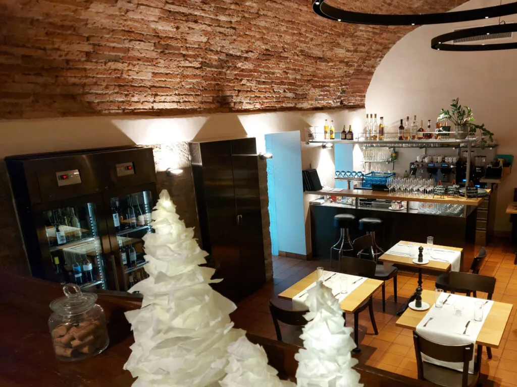 View from above into Klötzlikeller Bern with its impressive brick vault, white-clothed tables, and modern bar