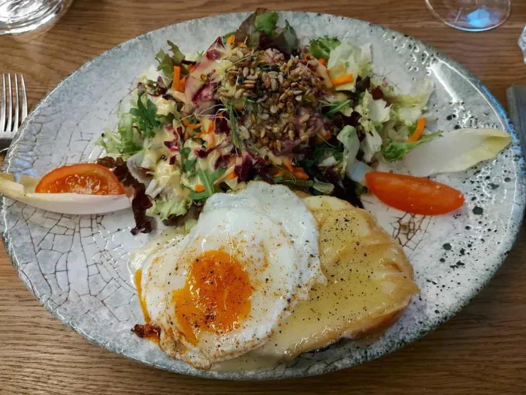 Cheese toast with a fried egg and mixed salad on a plate