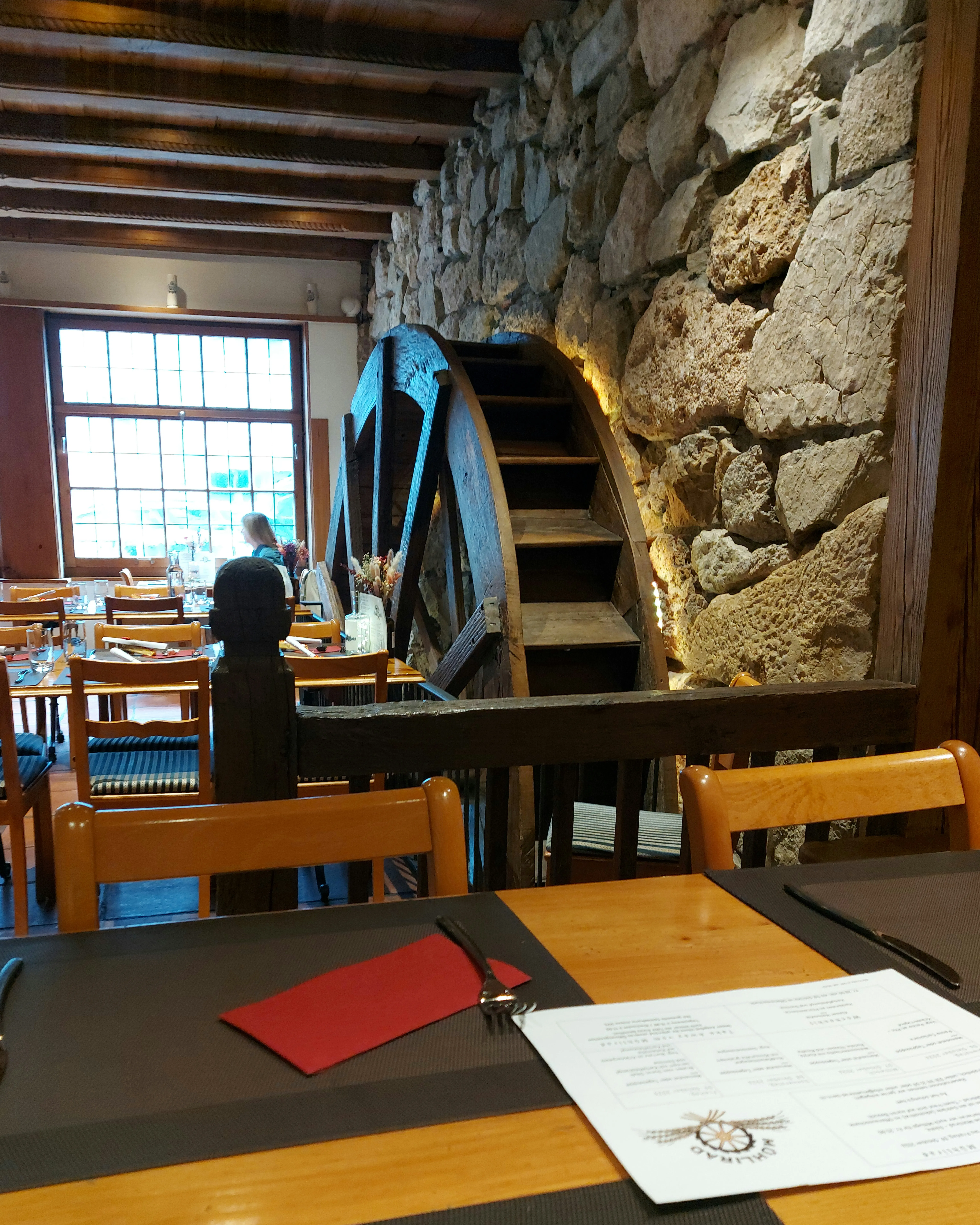 Innenraum des Restaurant Mühlirad mit Holzwänden und Mühlrad an der Wand