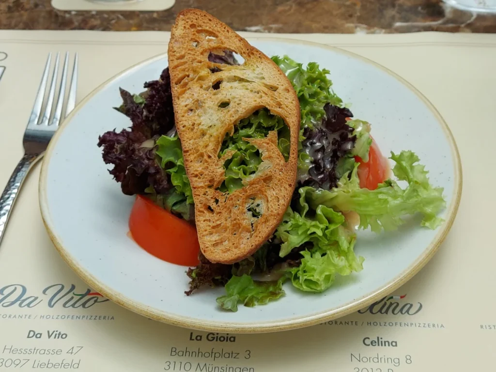 Gemischter Lollo-Salat mit Tomaten und goldbraun getoastetem Brot im Celina Bern
