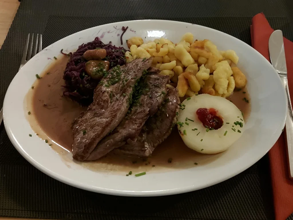 Traditional venison plate with venison cutlets, red cabbage, and spätzli at Restaurant Della Casa Bern.