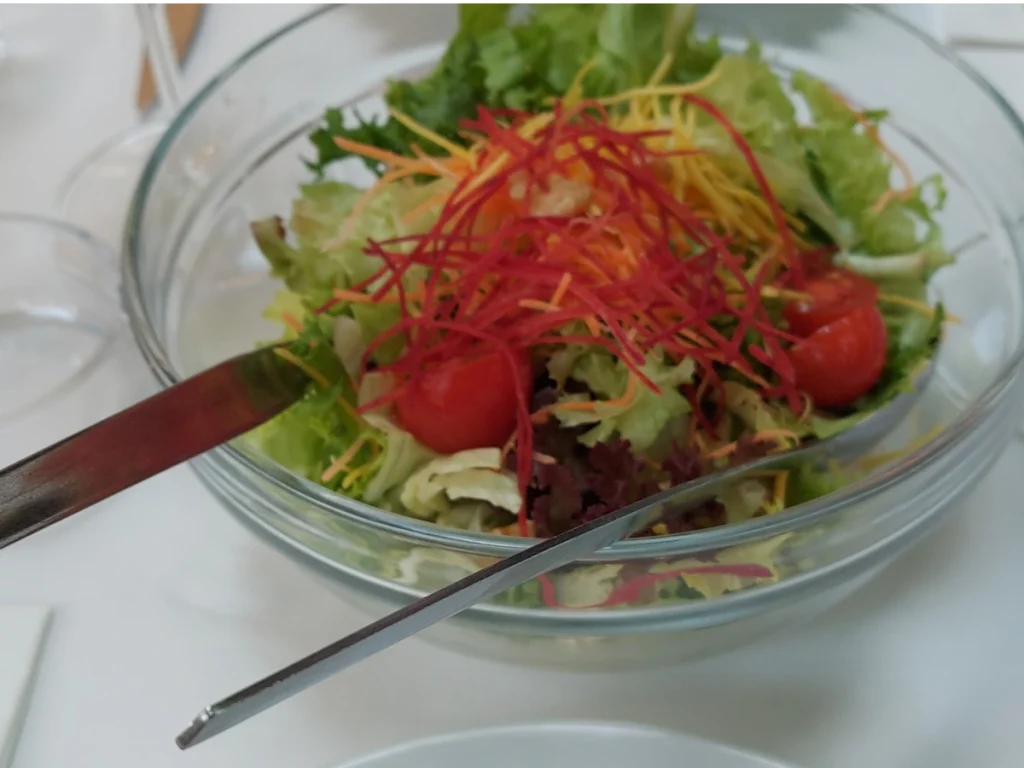Close-up einer Salatschüssel im Federal Bern mit frischem, noch nicht mit Sauce vermischtem Salat, bunten Möhrenstreifen und einigen Cherry-Tomaten.