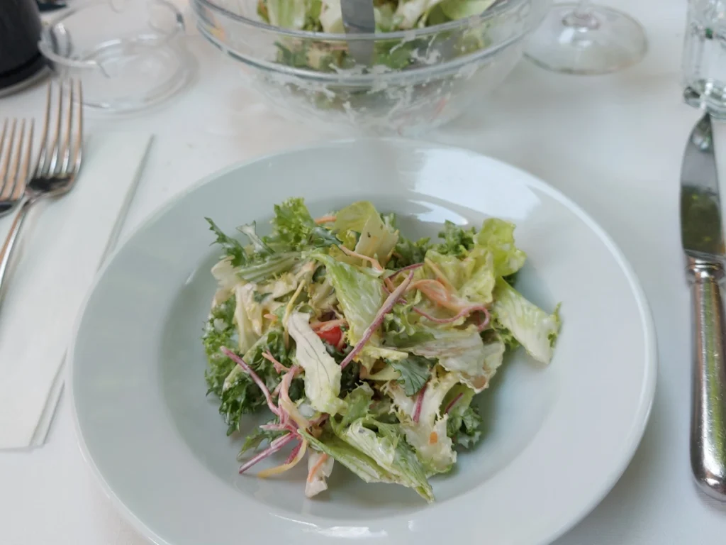 Ein Teller mit frisch mit französischem Dressing vermengten Salat, serviert im Federal Bern vor dem Hauptgang, dem Entrecôte.