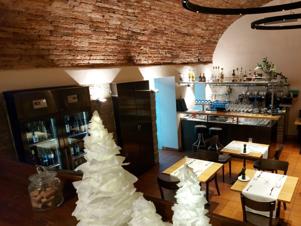 View from above into the Klötzlikeller Bern with its impressive brick vault, white-clothed tables, and modern bar in the background.