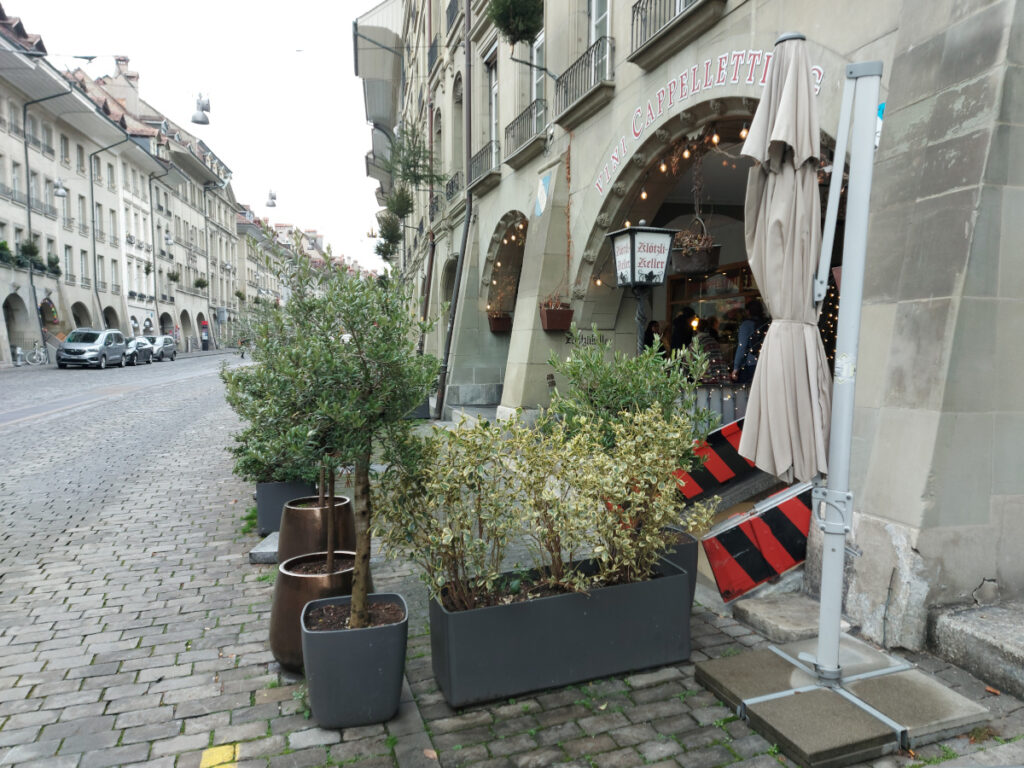 Exterior view of the entrance to the Klötzlikeller in Bern's Old Town with a view of the cobbled Gerechtigkeitsgasse and decorative green plants.