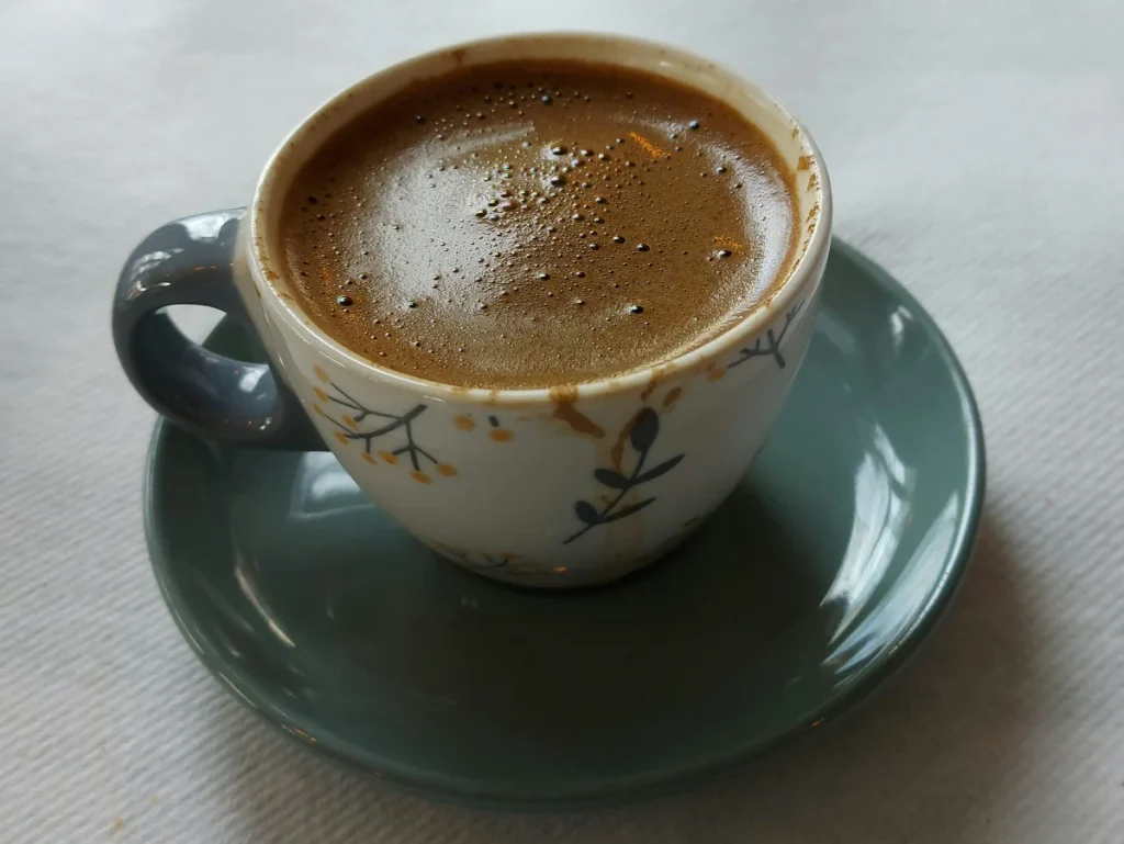 Tasse mit starkem, aromatischem und süssem griechischen Kaffee in traditioneller weiß‑blauer Tasse.