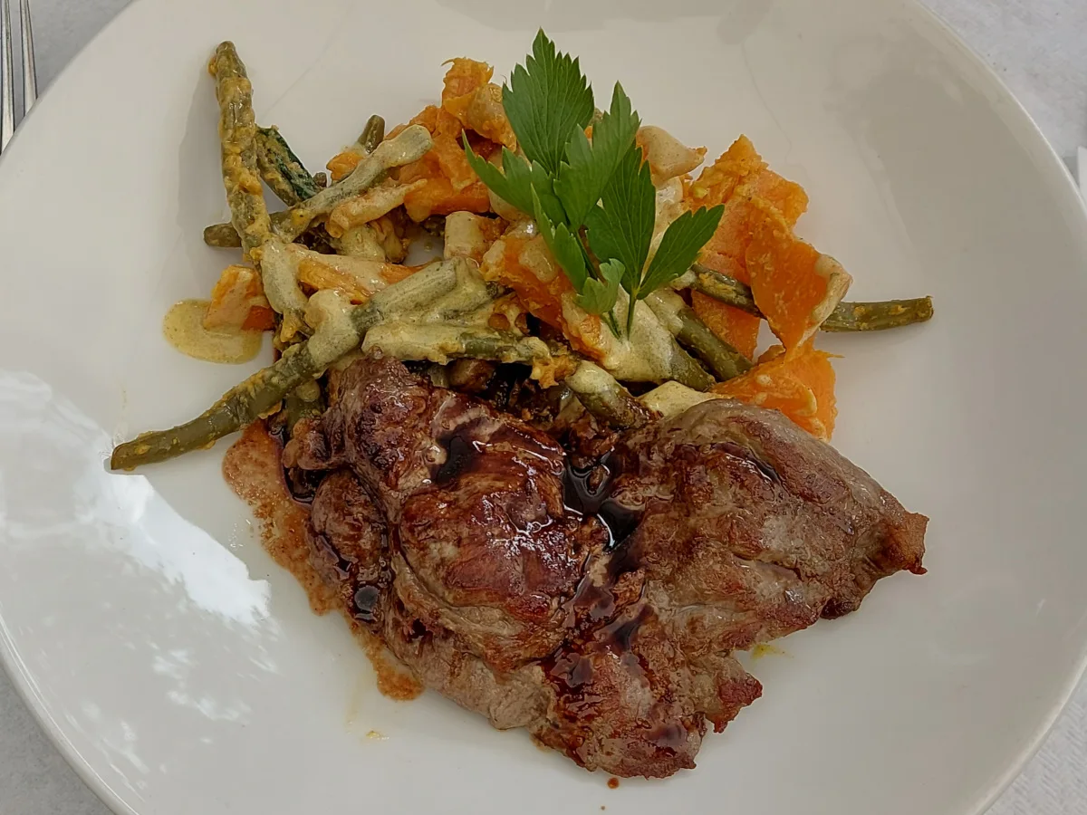 Spidersteak mit braunem Jus, Süsskartoffelsalat mit grünen Bohnen und cremigem Dressing auf weißem Teller.