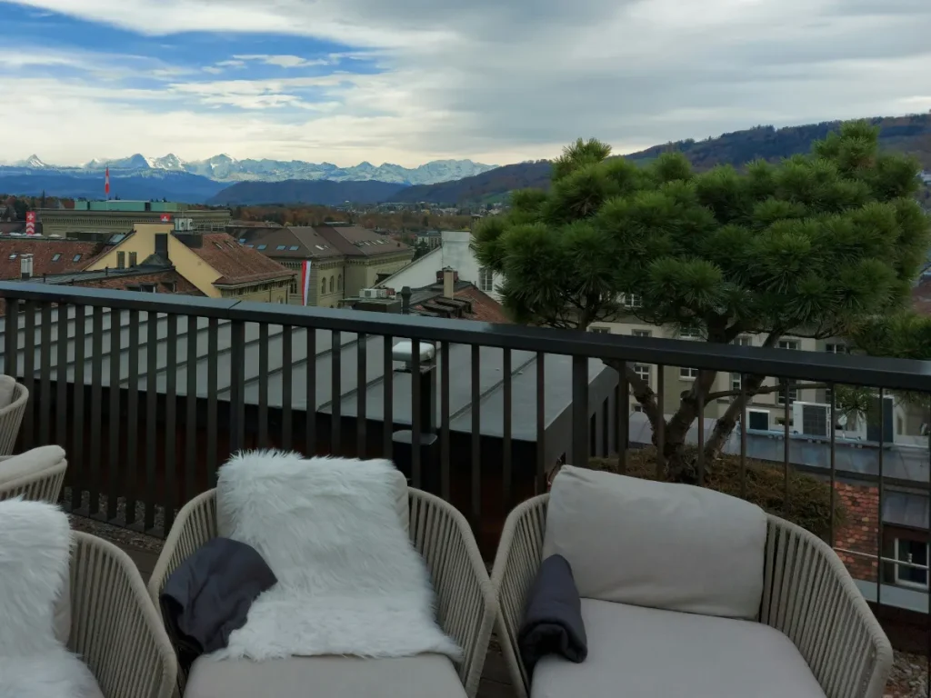 Zwei beige Balkon-Sessel auf der Nido Bern Terrasse mit Panoramablick auf die Berner Alpen: Eiger, Mönch und Jungfrau.