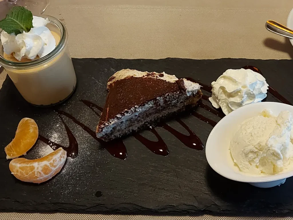 Café Gourmand at Ratskeller Bern: Dessert selection with caramel crème, Christmas tiramisu, and vanilla ice cream on a slate plate.