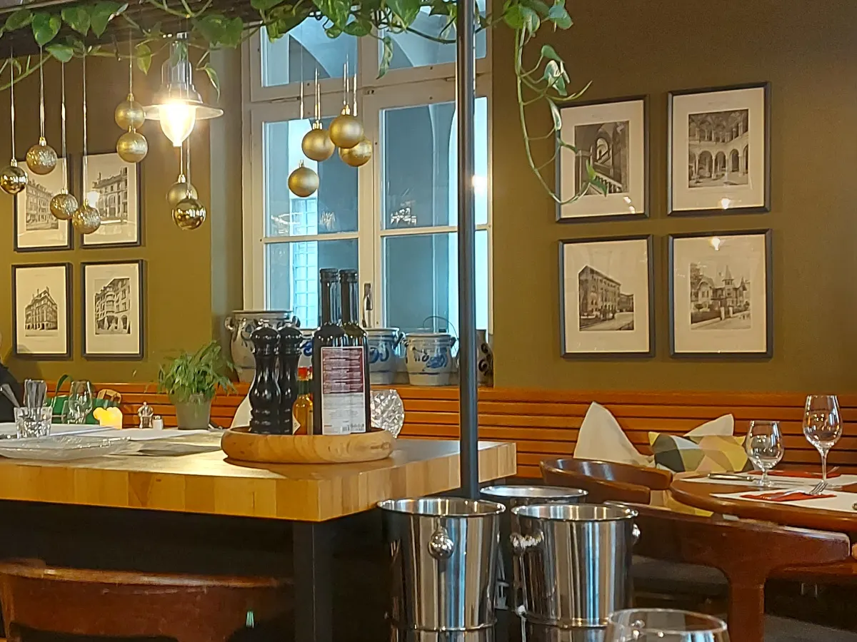 Elegant interior of Ratskeller Bern: Olive green walls, photos of Bern's Old Town, and stylishly set tables.