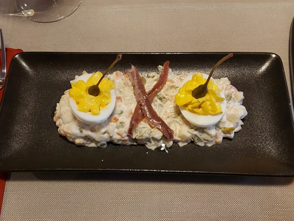 Russian Salad from Ratskeller Bern: Vegetable and potato dice in a creamy sauce, garnished with egg, anchovies, and capers.