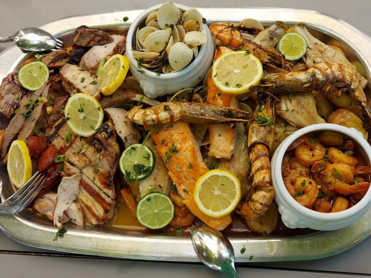 Authentische portugiesische Grillplatte "Terra e Mare" mit gebratenen Rinds- und Schweinesteaks, Lachsfilets, Garnelen, Riesencrevetten und Muscheln, dekoriert mit Kräutern und Zitrusfrüchten – serviert im Restaurant Brunnhof Bern.
