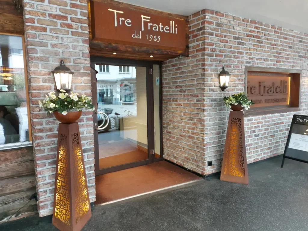 Eingang des Tre Fratelli Bern mit Ziegelsteinmauern und dem Schriftzug "Tre Fratelli" über der Tür.