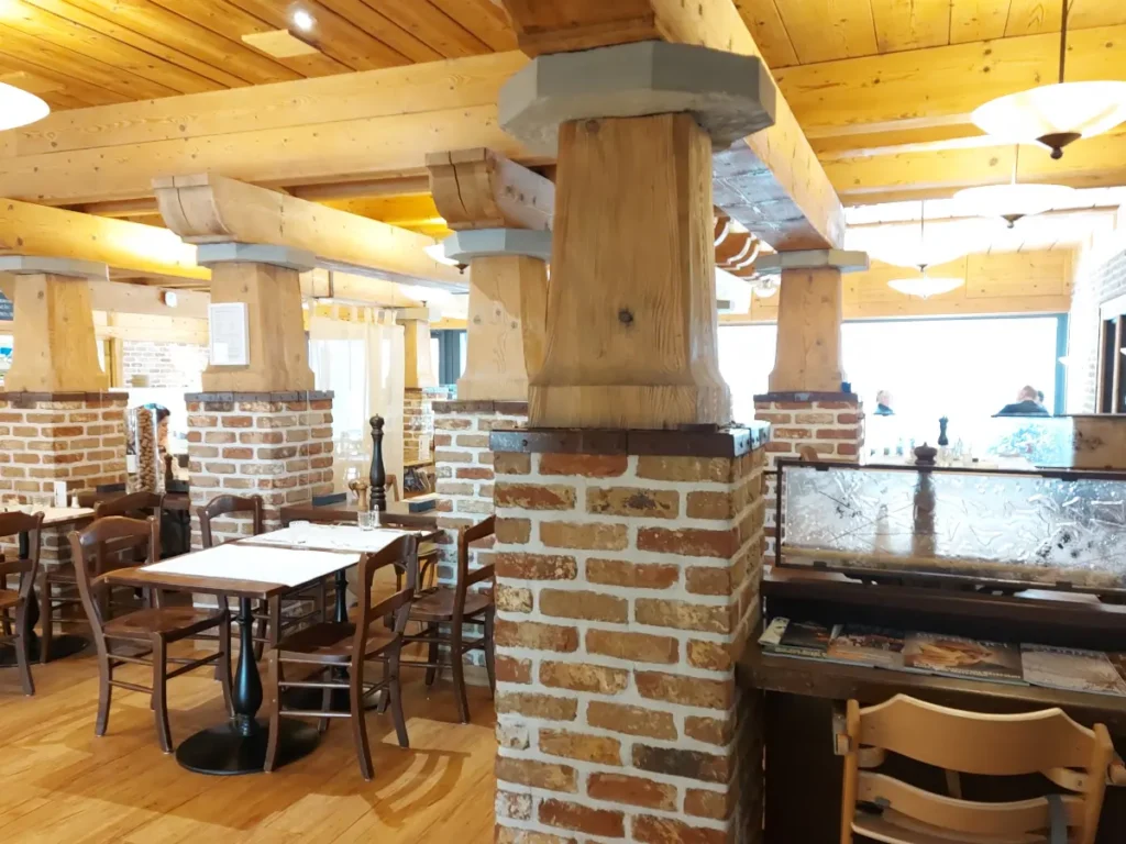 Urchiges Interieur des Tre Fratelli Bern mit Ziegelstein- und Holzstützen, Holztischen und -stühlen.