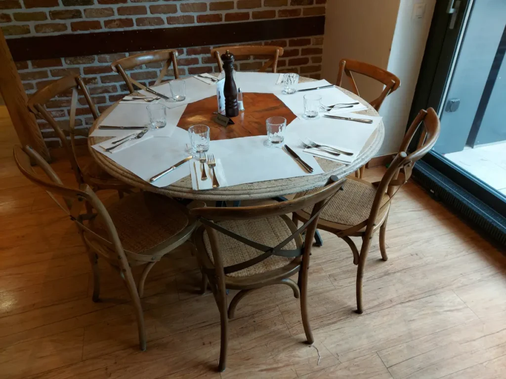 Gedeckter Holztisch mit sechs schlanken Holzstühlen im Tre Fratelli Bern, inklusive weisser Tischsets und Kerze.